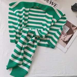 Detail of green and white striped knit shawl with H.STUDIO woven label and ribbed edges