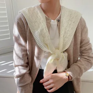 Close-up of cream hollow knit shawl with rhombic texture over a cardigan