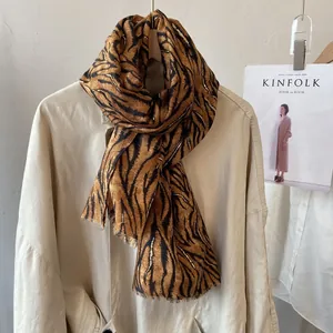 Detail of tiger print scarf with gold foil threads and raw edges on cream shirt