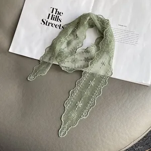 Detail of light green floral lace scarf with delicate embroidery and scalloped edges