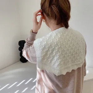 Close-up of a white knit decorative shawl collar with diamond hollow pattern and wavy edge