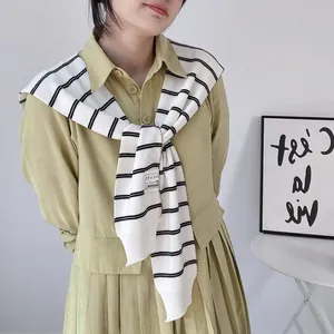 Close-up of the black and white striped knitted shawl draped over a pleated dress