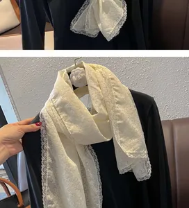 Détail d'une écharpe en dentelle crème avec motifs floraux et bordure festonnée élégante