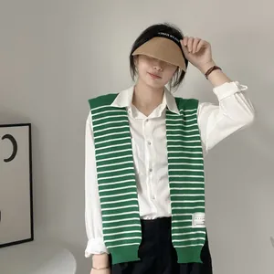 Close-up of green and white striped knit shawl draped over a white long sleeve shirt