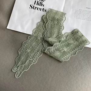 Detail of light green hollow lace scarf with floral embroidery and scalloped edges