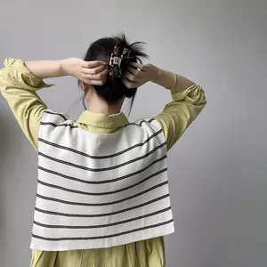 Detail of a vintage striped shawl layered over a green shirt with a tortoise hair claw clip