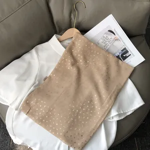Détail d'une écharpe marron clair en coton avec imprimé floral doré sur chemise blanche