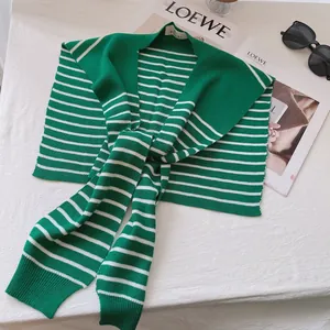 Detail of green and white striped knit shawl accessory on white table background