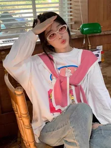 Detail of white long sleeve T-shirt featuring a cartoon cat print and pink knit shawl