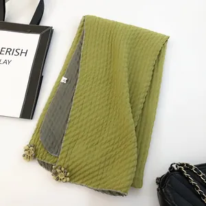 Close-up of dual-color linen scarf with waffle texture and woven flower pendant details
