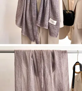 Detail view of lavender tie-dye linen scarf with pleated texture and brand tag