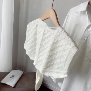 Close-up of white cable knit shawl vest featuring intricate openwork and soft cotton texture