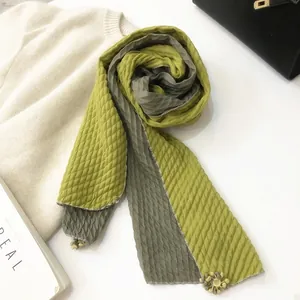 Detail of olive green pleated scarf with handcrafted floral tassel charm and texture