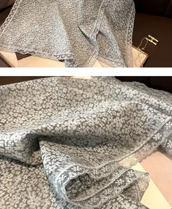 Détail d'une écharpe fleurie gris clair avec bordure en dentelle délicate et tissu doux