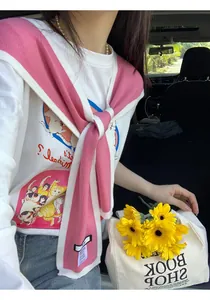 Detail of pink striped knit shawl tied over a white graphic tee and blue jeans