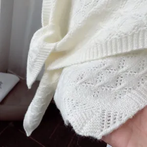 Detailed close-up of ivory hollow-out crochet knit shawl showing diamond texture and lace-up