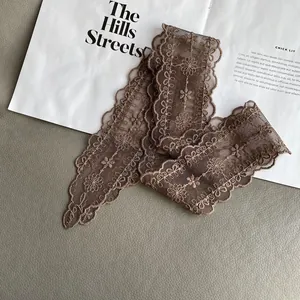 Close-up of brown lace trim with floral embroidery and wavy edges on a textured background