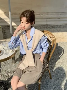 Dettaglio di uno scialle in lana australiana su camicia azzurra e pantaloncini kaki