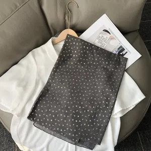 Détail du tissu d'écharpe gris foncé avec motifs floraux dorés sur une chemise blanche