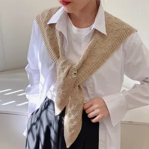 Detail of beige knit shawl with hollow diamond pattern worn over a white shirt