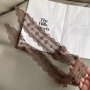 Close-up of a brown lace ribbon with floral embroidery and scalloped edges on a book