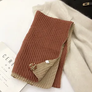Detail of bicolor cotton linen scarf with diamond texture and 3D floral pendant accents
