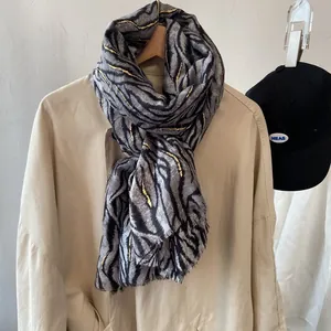 Detail of zebra pattern scarf with gold foil accents draped on a beige trench coat