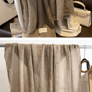Detail of khaki pleated cotton linen scarf with textured fabric and care label detail