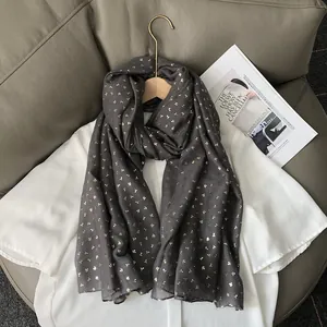Gros plan d'une écharpe gris foncé en coton et lin avec des motifs de trèfles dorés