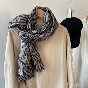 Close-up of zebra pattern scarf with metallic gold accents and delicate fringe detail