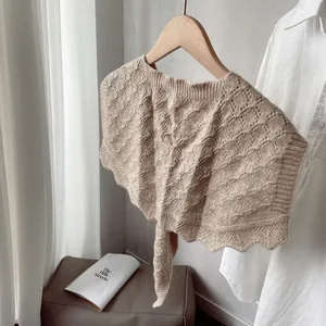 Detailed macro view of beige knit shawl with hollow diamond pattern and scalloped edges