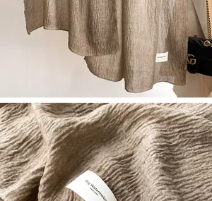 Detail showing the crinkled texture of the khaki linen scarf and stitched brand tag