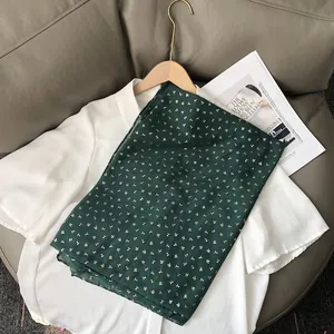 Détail du châle vert foncé léger avec motifs cerises dorés sur tissu de qualité