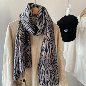 Detail of zebra pattern scarf with gold foil accents draped over a beige trench coat