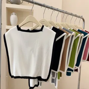 Detail of square-neck knitted vests in multiple colors hanging on a minimalist metal rack