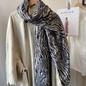 Detail of tiger pattern scarf with gold embroidery on beige trench coat display