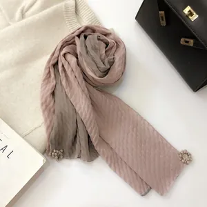 Close-up of pink and grey linen scarf with pleated texture and floral pendant details