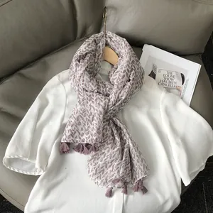 Lightweight scarf with purple leaf print and tassels on a wooden hanger with magazine