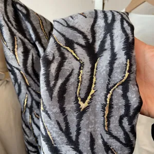 Detail of soft leopard print scarf featuring golden foil texture and animal patterns