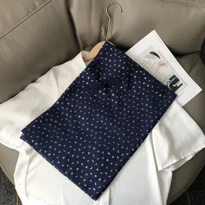 Gros plan sur l'écharpe en coton et lin bleu foncé avec d'élégants motifs de cerises dorés