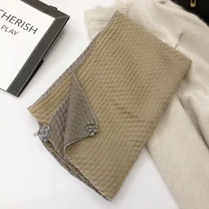 Detail of dual-tone linen scarf with ruffled texture and grey floral pendant decor