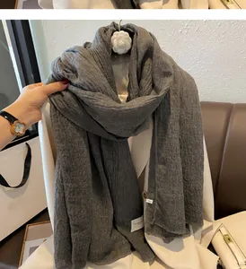 Detailed view of dark gray crinkled cotton scarf with a rectangular white woven label