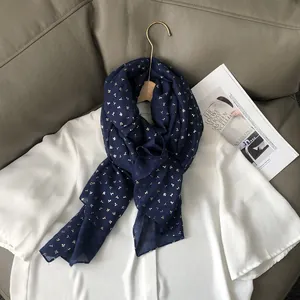 Texture détaillée d'une écharpe en lin bleu marine avec imprimés cerises dorés sur cuir