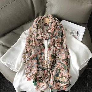 Böhmischer Schal mit Blumenmuster und Quasten über weißem Hemd auf einem Ledersofa