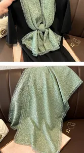 Détail d'une écharpe fleurie vert clair avec bords en dentelle et tissu imprimé doux