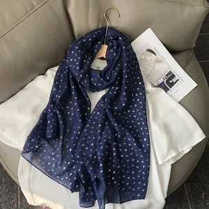 Détail d'une écharpe bleu foncé en lin avec motifs de trèfles dorés sur cuir de luxe