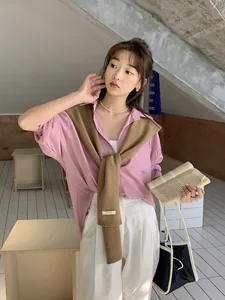Dettaglio dello scialle in lana australiana sopra camicia rosa e pantaloni bianchi larghi