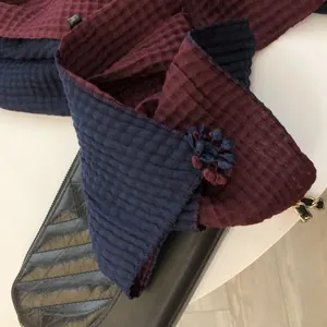 Macro detail of bicolor waffle weave cotton scarf featuring handmade 3D floral accents