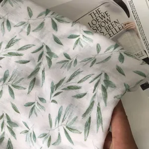 Detail shot of linen cotton scarf with elegant green olive leaf prints and soft texture