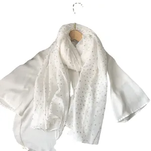 Écharpe élégante en coton et lin blanc avec imprimé trèfle doré sur un cintre en bois